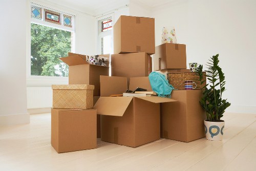 Professional movers carrying packed boxes through a London property hallway
